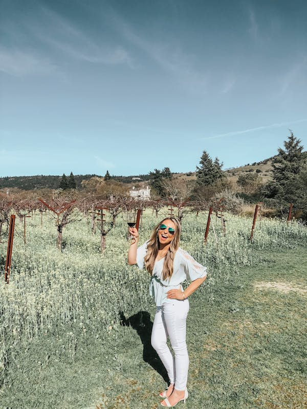 A woman enjoys a glass of wine in a vineyard.